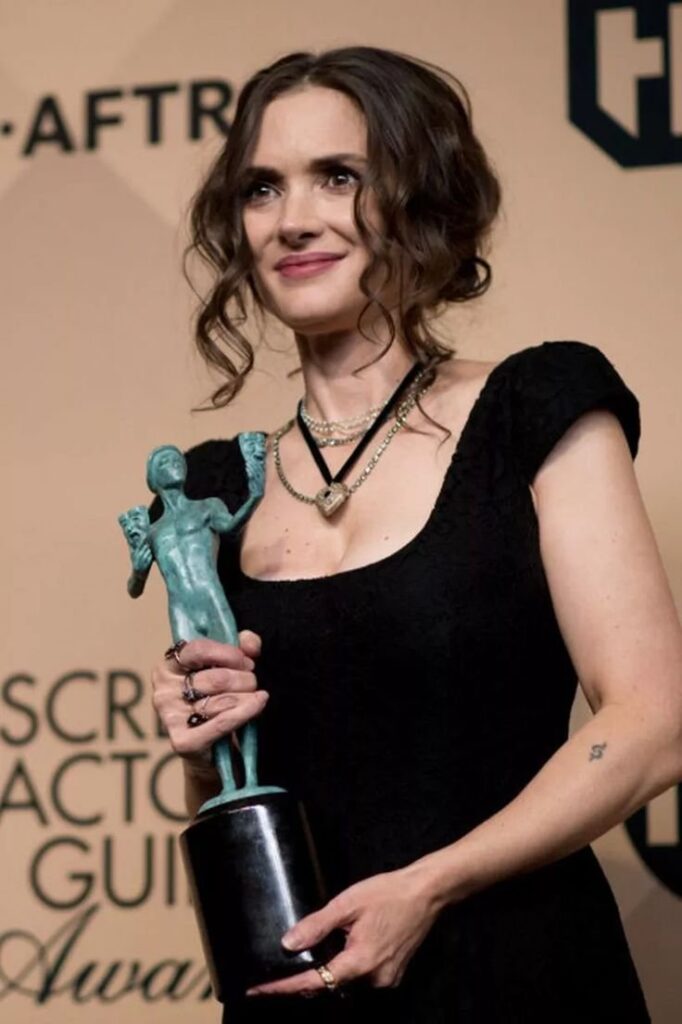 Winona Ryder looking very pretty in black dress with wonderful award